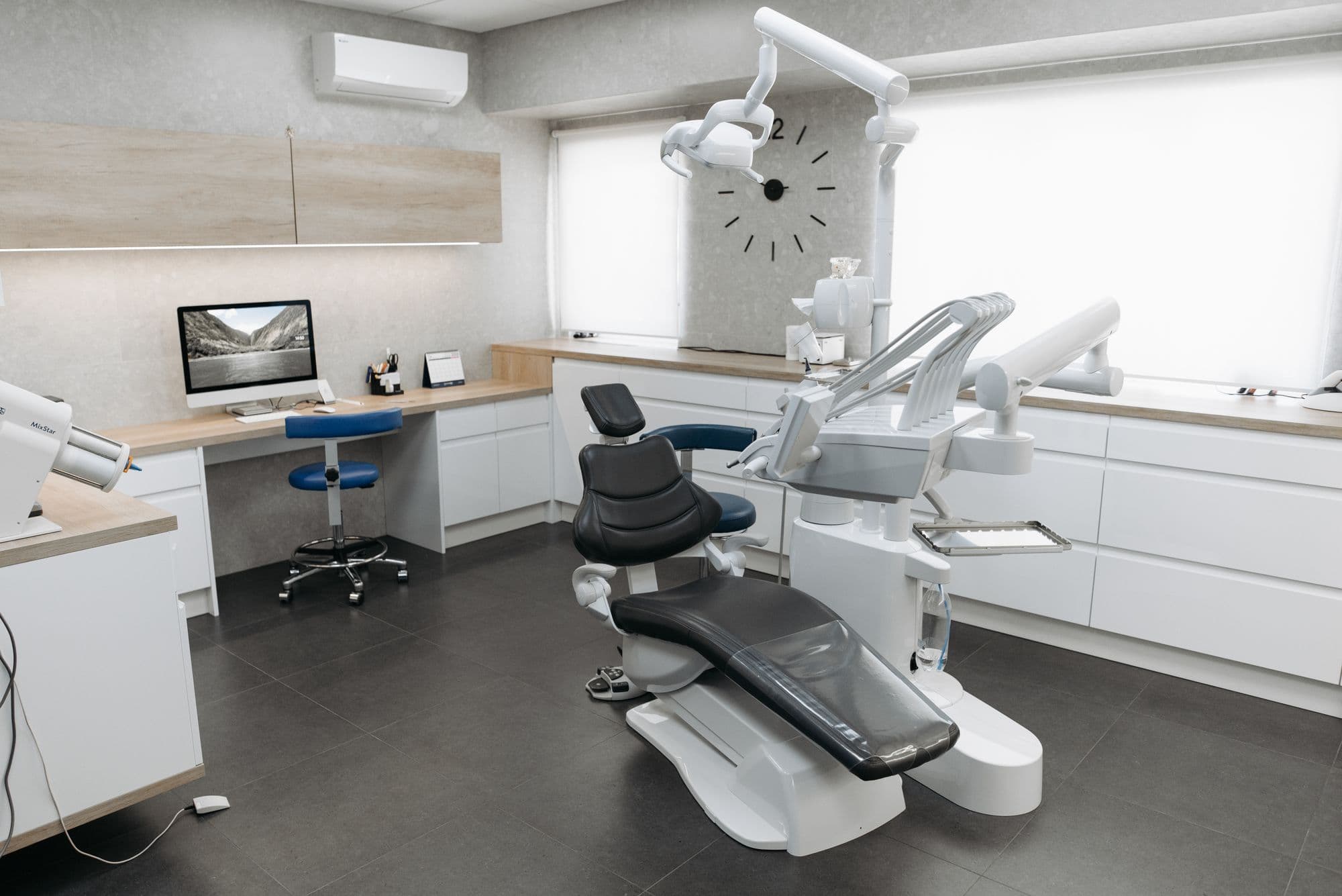 Consultório claro com cadeira odontológica moderna, bancada e janela grande
